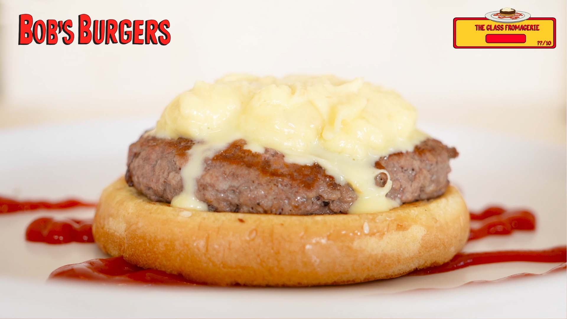 Open-faced patty under thick cheese cream on a bun half, ketchup streaked across the plate