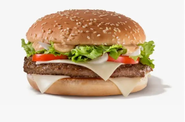 Close-up of a beef patty with Swiss cheese in a sesame seed bun
