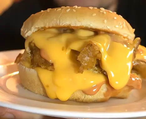 Close-up of fried chicken with melted American cheese in a brioche bun