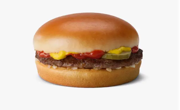 Close-up of a beef patty with diced onion and pickles in a soft burger bun