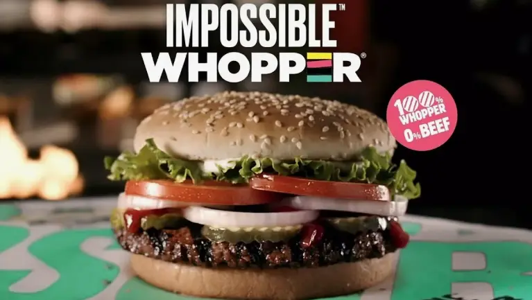 Close-up of a plant-based patty with tomato slices in a sesame seed bun