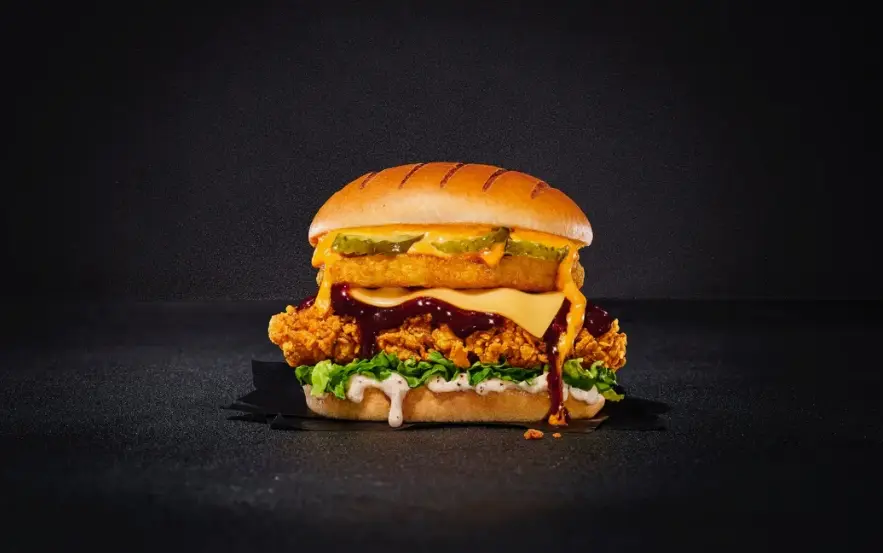 Close-up of a breaded chicken fillet with melted cheddar in a soft burger bun