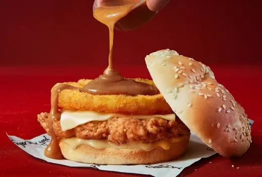 Close-up of a breaded chicken fillet with melted cheddar in a soft burger bun