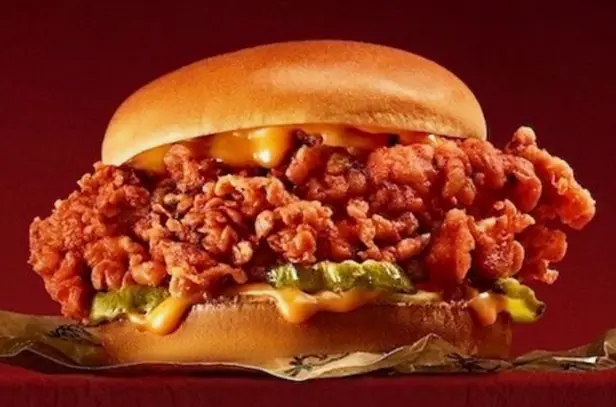Close-up of a breaded chicken fillet with pickles in a brioche bun