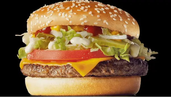 Close-up of a beef patty with melted American cheese in a sesame seed bun