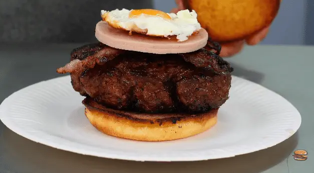 Thick beef patty under a ham slice and a fried egg on a toasted bun