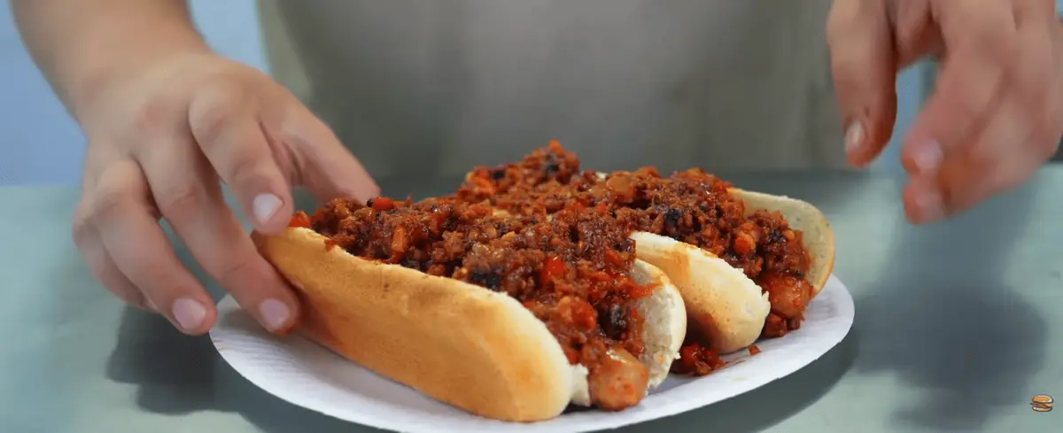 Close-up of a beef patty with bacon and diced onion in a hot dog bun