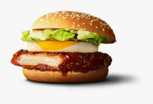 Close-up of a beef patty with shredded lettuce in a soft burger bun