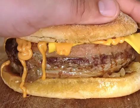 Close-up of a beef patty with melted cheddar and bacon in a brioche bun