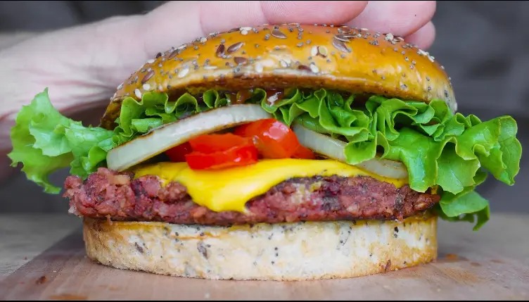 Close-up of a lentil patty with melted American cheese in a soft burger bun