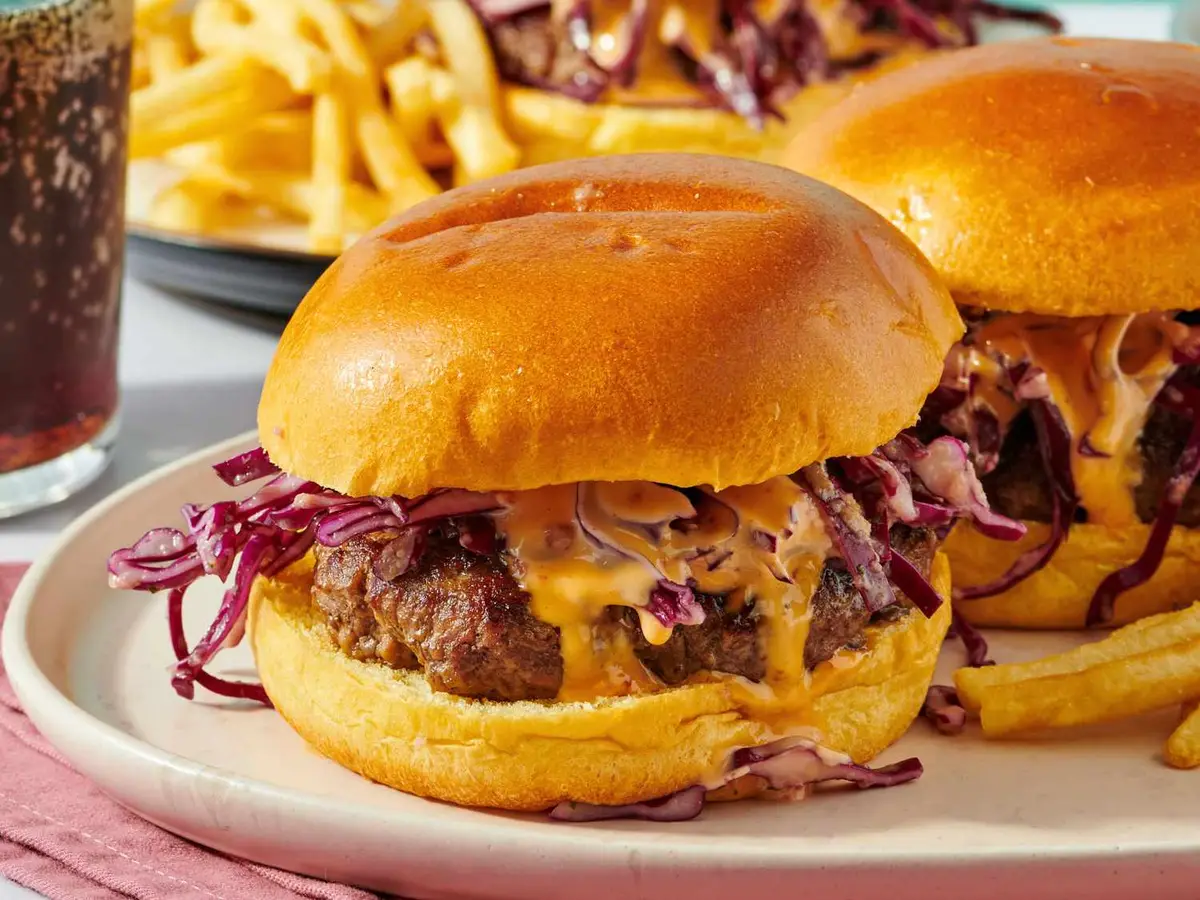 Close-up of a beef patty with avocado and slaw in a brioche bun
