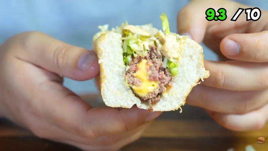 Close-up of a beef patty with melted American cheese in a hot dog bun
