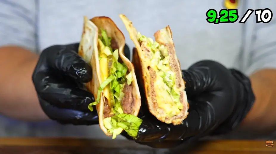 Close-up of a smashed beef patty with melted American cheese and pickles in a tortilla