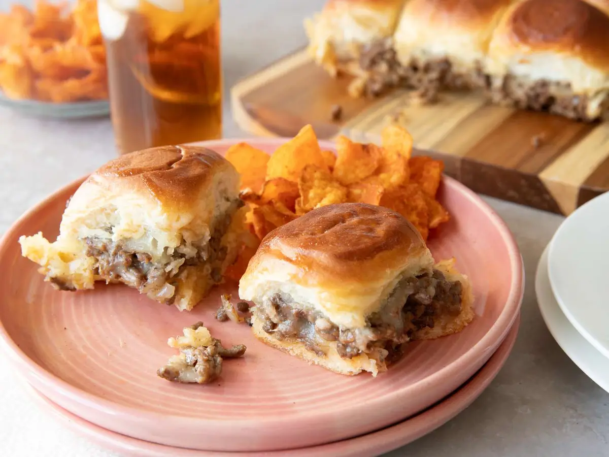 Close-up of a beef patty with Monterey Jack and diced onion in a slider roll