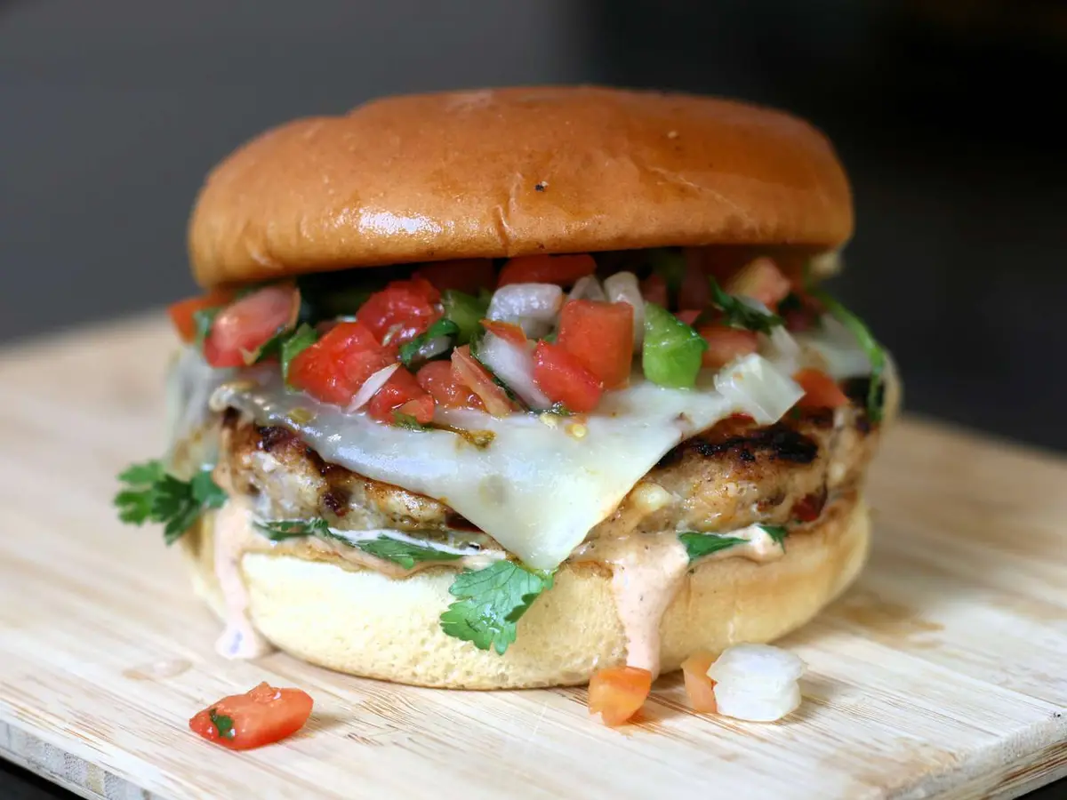 Close-up of a chicken patty with queso fresco in a soft burger bun