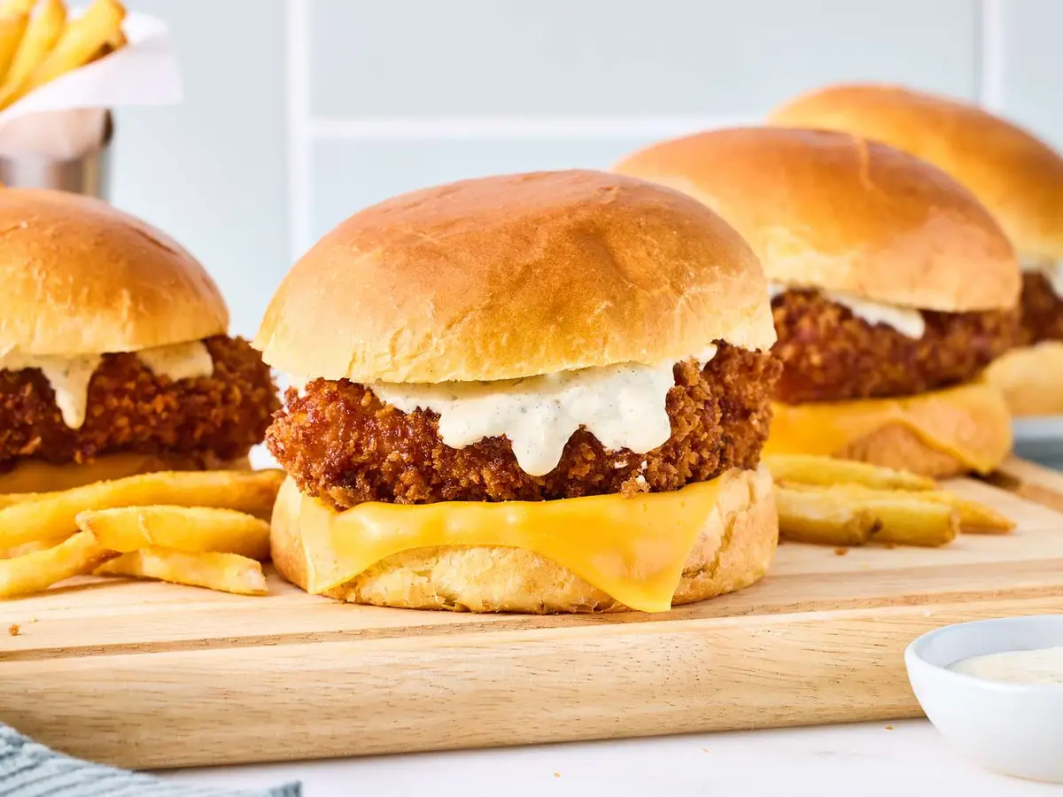 Close-up of a battered fish fillet with melted American cheese in a soft burger bun
