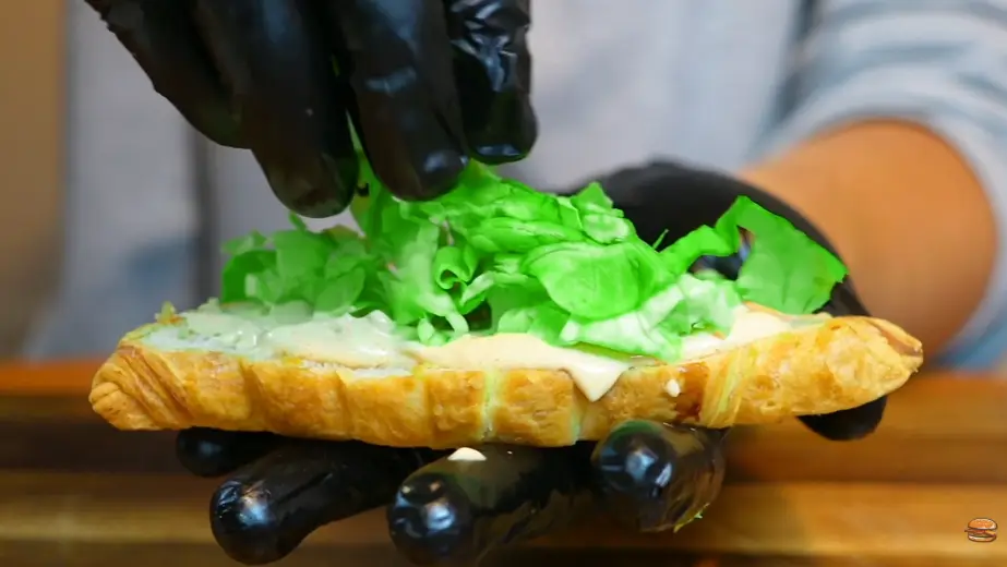 Step 6: Build the burger. Bottom croissant, sauce, lettuce, first