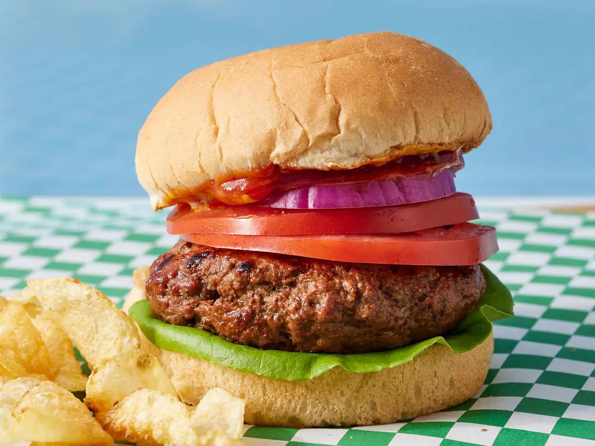 Close-up of a beef patty served open, shot close on a plain background