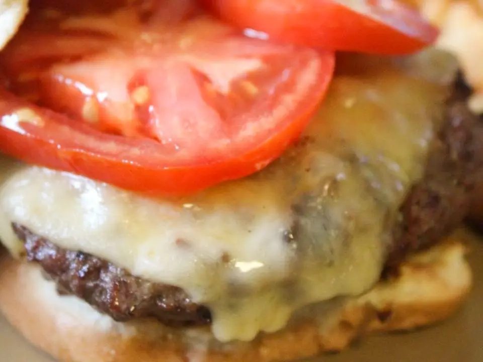 Close-up of a beef patty with melted cheddar and bacon in a soft burger bun