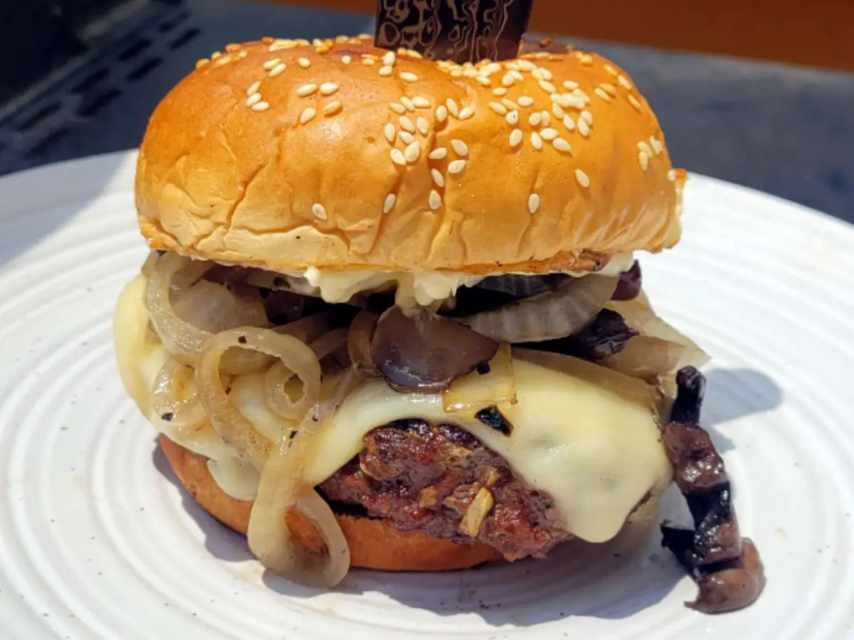 Close-up of a portobello cap with havarti and sauteed mushrooms in a soft burger bun