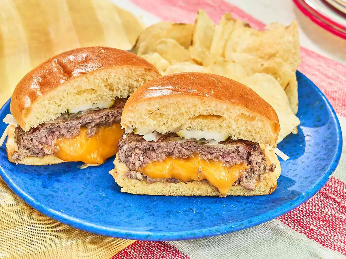 Close-up of a beef patty with melted cheddar in a soft burger bun
