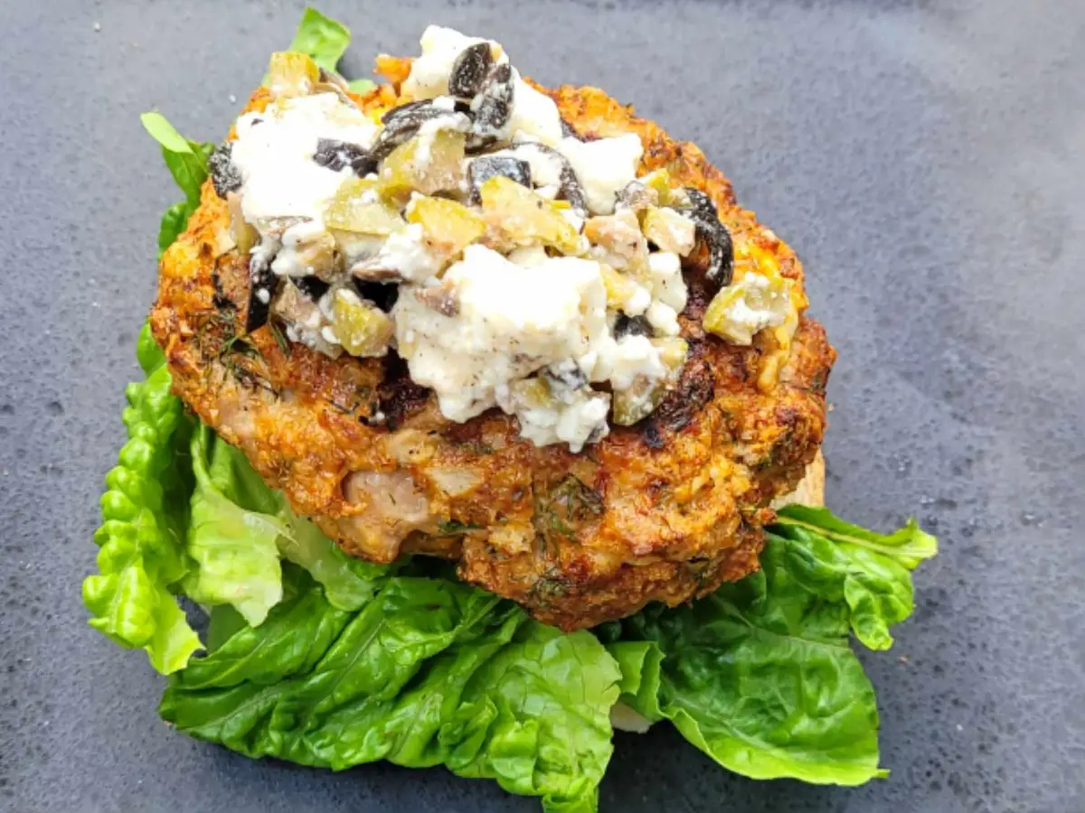 Close-up of a turkey patty with crumbled feta, olives and diced onion