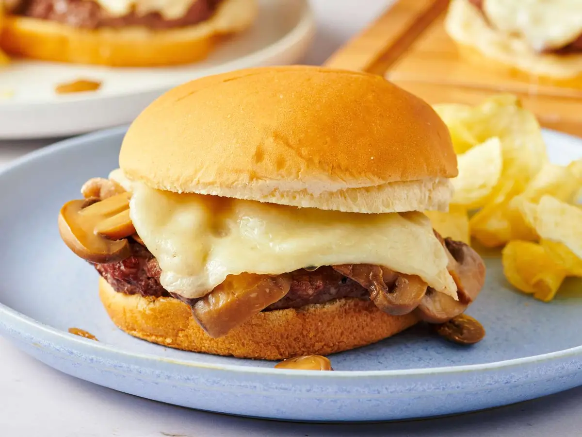 Close-up of a beef patty with Swiss cheese in a soft burger bun