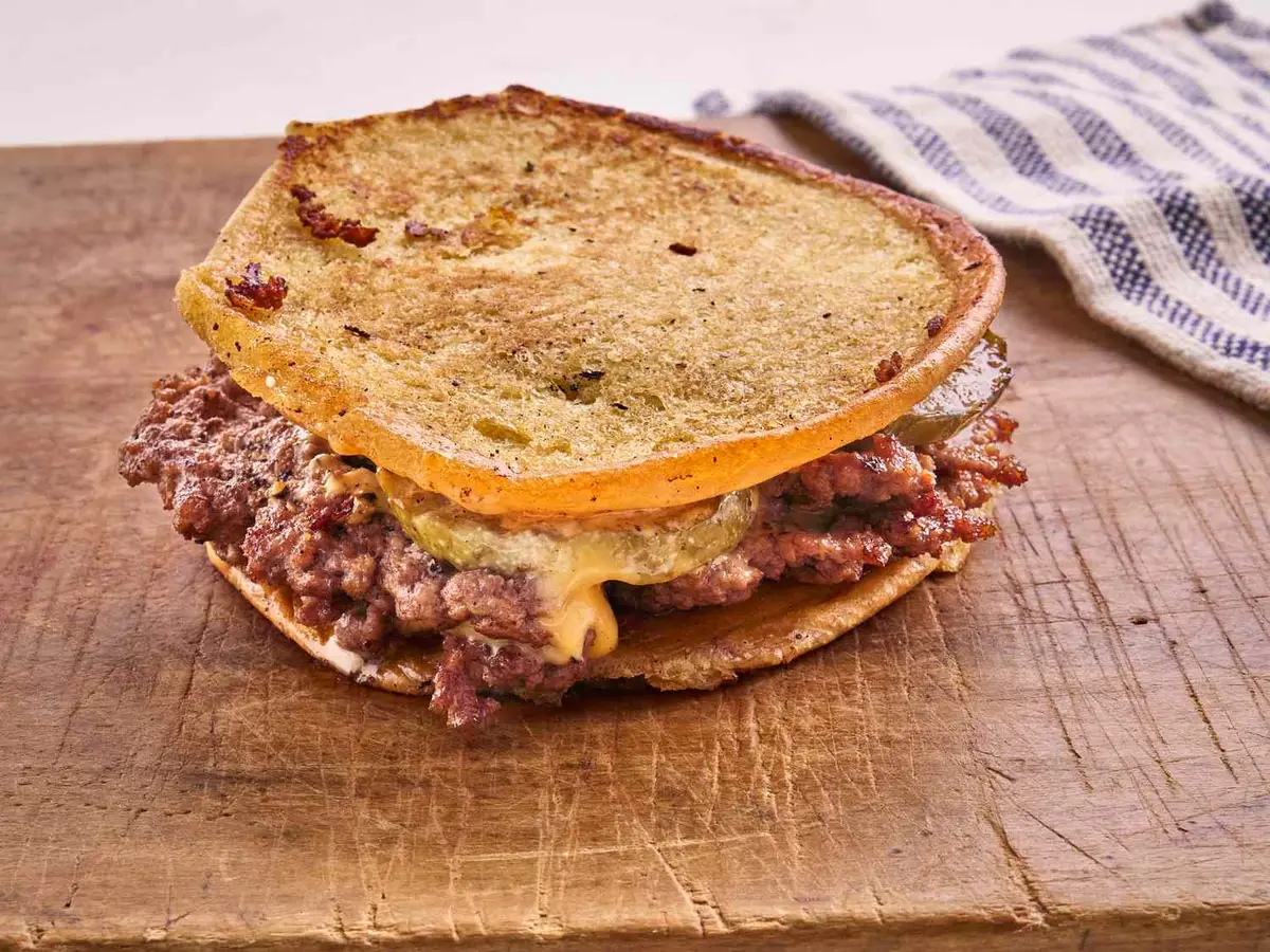 Close-up of a beef patty with melted American cheese in a soft burger bun