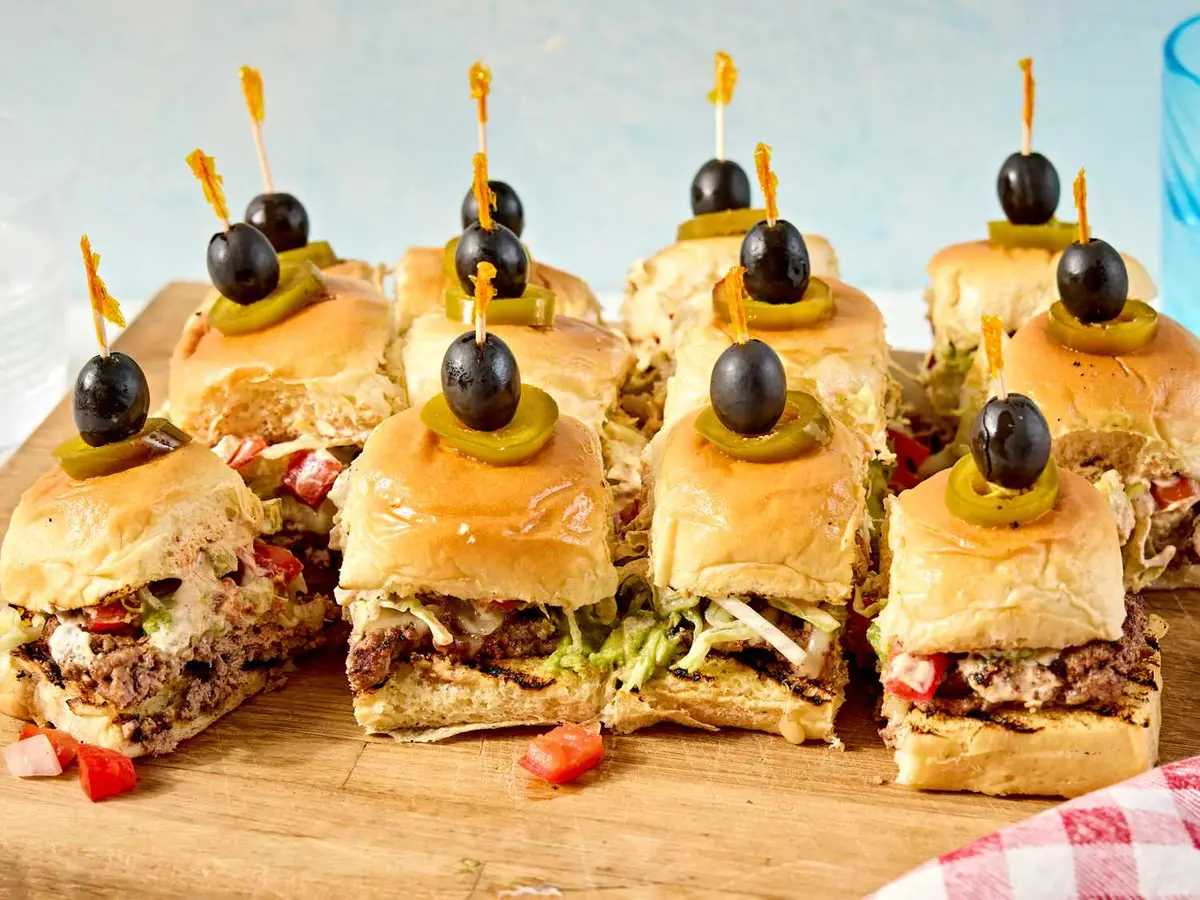 Close-up of a beef patty with Monterey Jack and tomato slices in a slider roll
