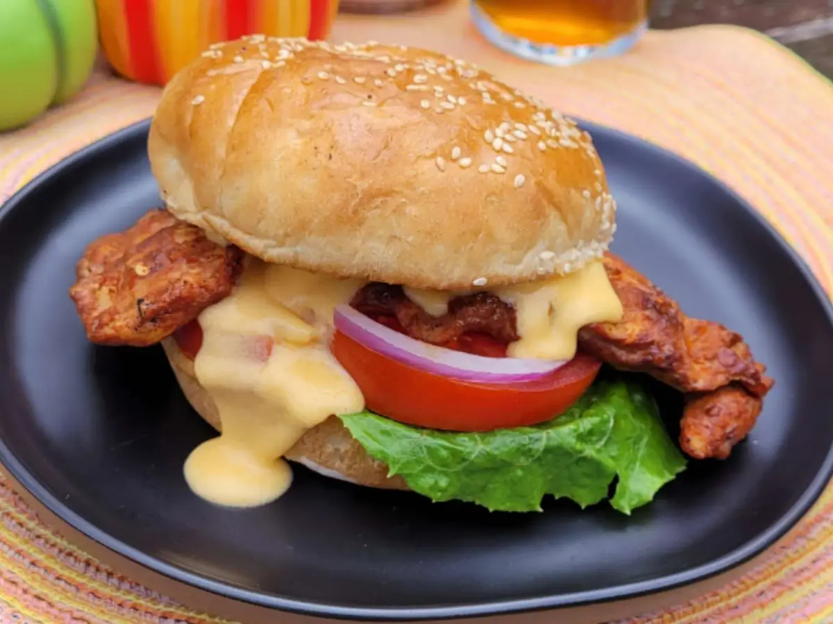 Close-up of a breaded chicken fillet with melted cheddar in a soft burger bun