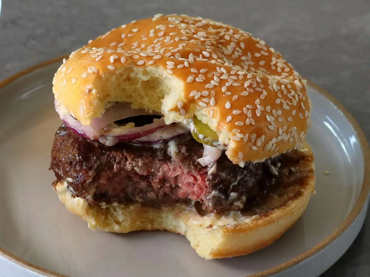Close-up of a beef patty with avocado served open