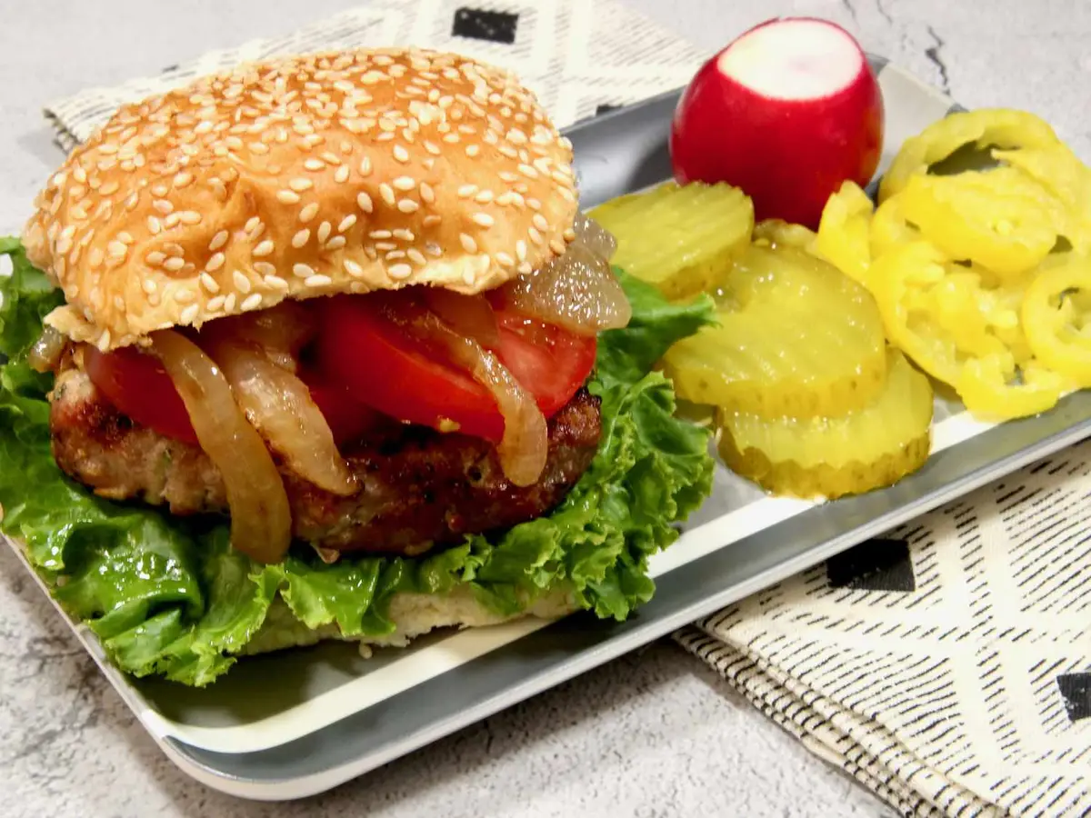 Close-up of a turkey patty with red onion rings in a soft burger bun