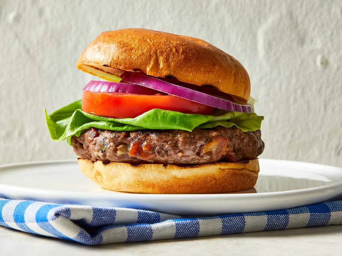 Close-up of a venison patty with bacon in a soft burger bun